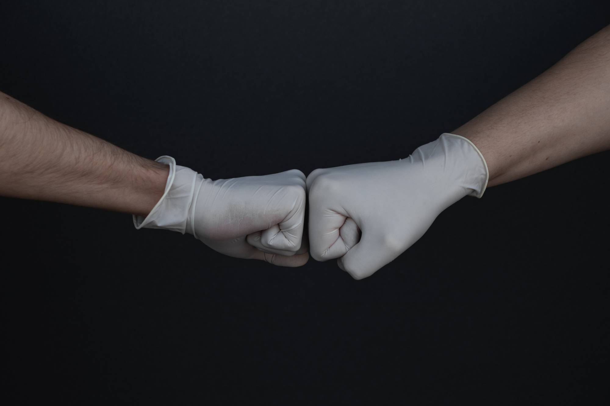 Two hands in gloves doing a fist bump